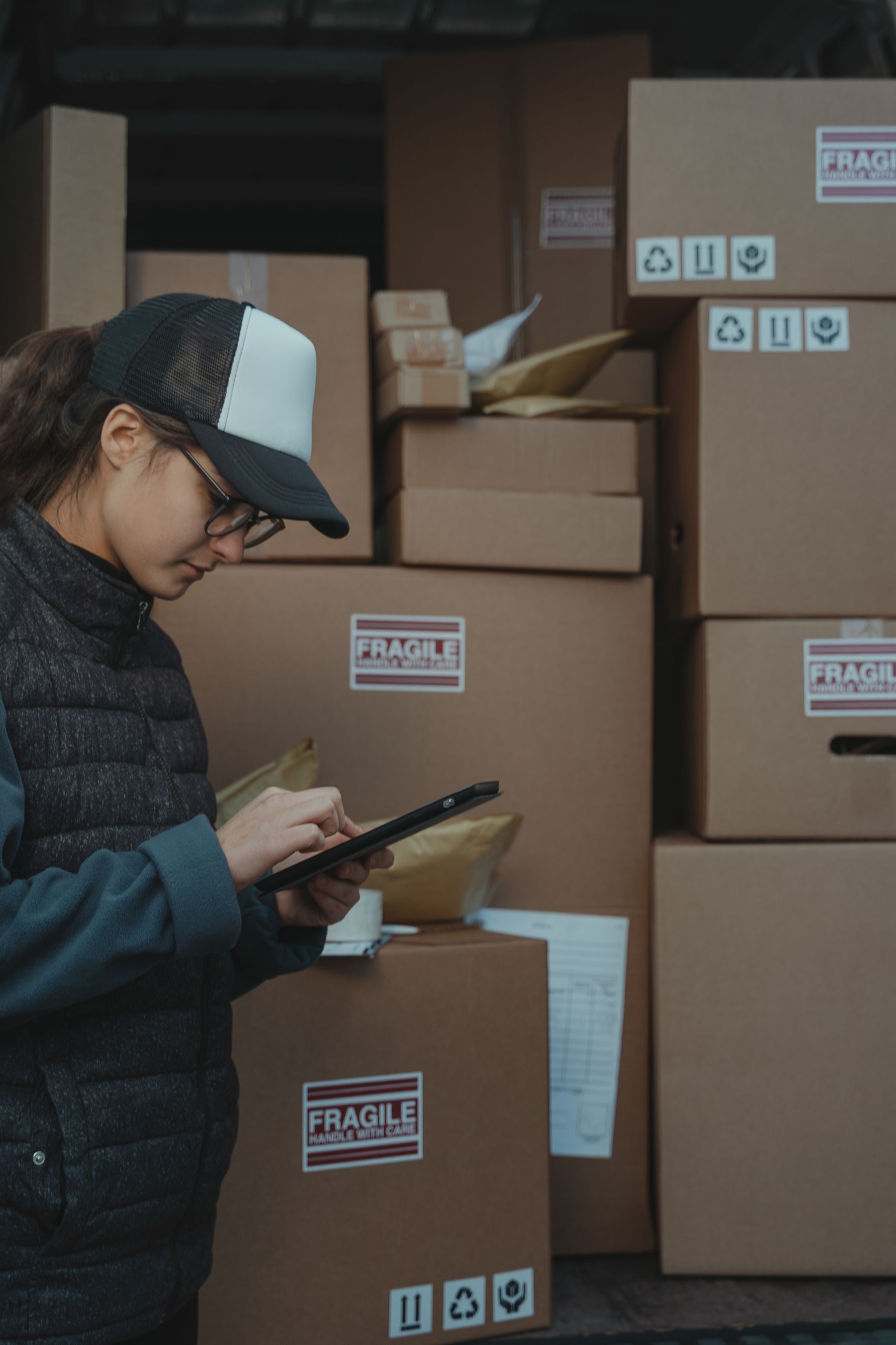 Warehouse employee reviewing inventory on a tablet beside cartons